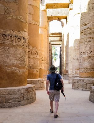 A low angle shot of a male walking between columns in  Karnak Temple in Egypt